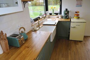 Una cocina con encimera de madera, un tostador antiguo, una cafetera y un refrigerador pequeño.