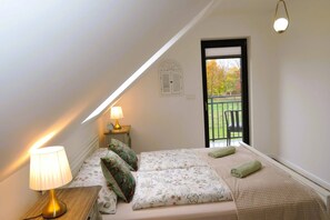 A bedroom with a bed, a nightstand, a lamp, a window with a view, and a door. - Green Hill Domyslow, 6 persons (Kołczewo)