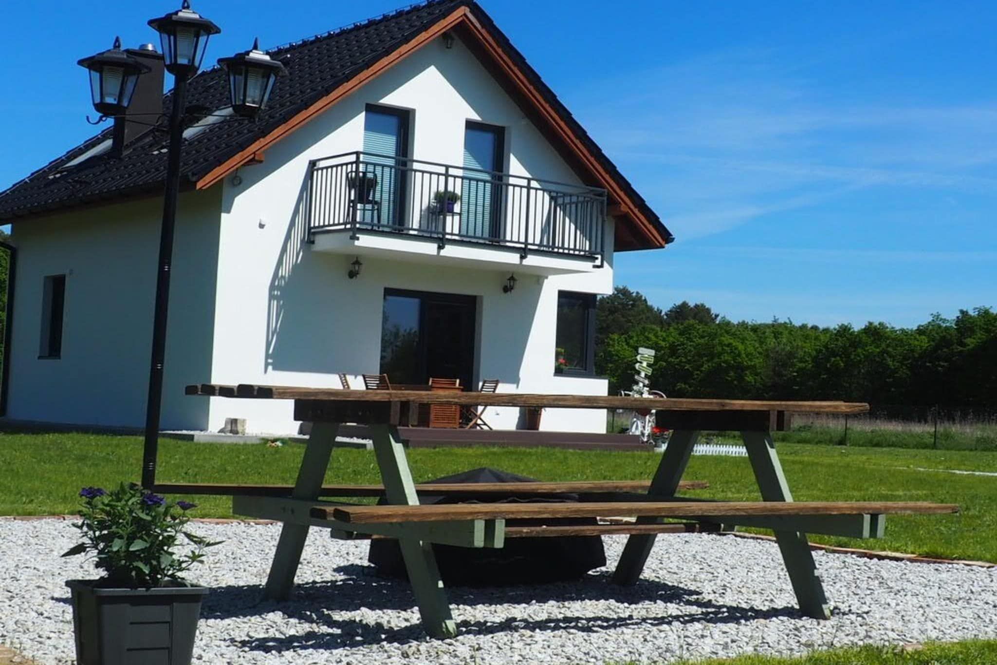 A two-story house with a balcony, a patio table, and a small garden area.