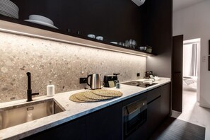 A modern kitchen with a granite countertop, stainless steel sink, and a coffee machine. - Shadows of Love - MyHomeinComo (Como)