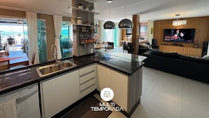 Una cocina moderna con una mesa de comedor de vidrio, armarios blancos y un horno empotrado.