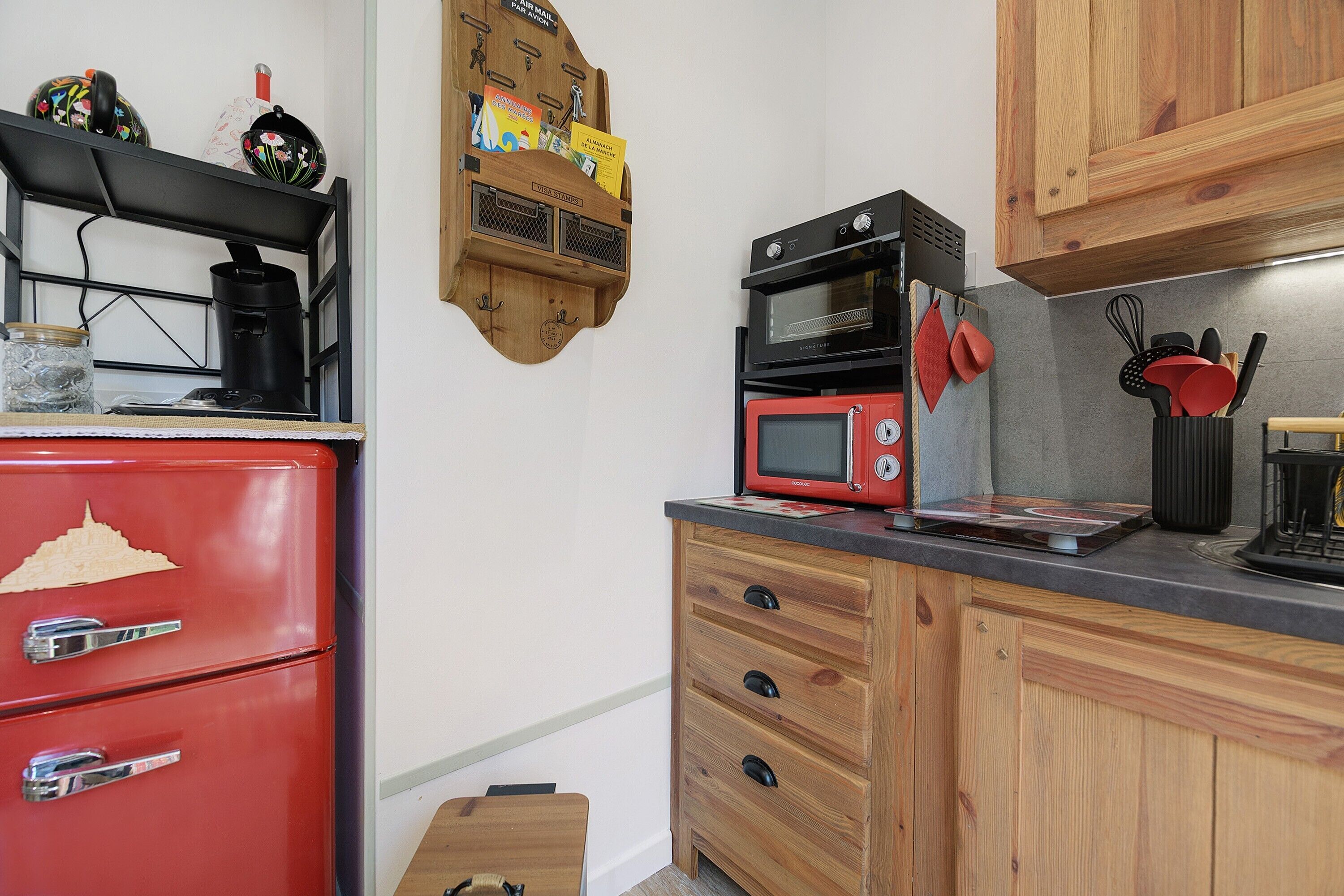 A compact kitchen with a red refrigerator, a microwave, and a wooden cabinet.