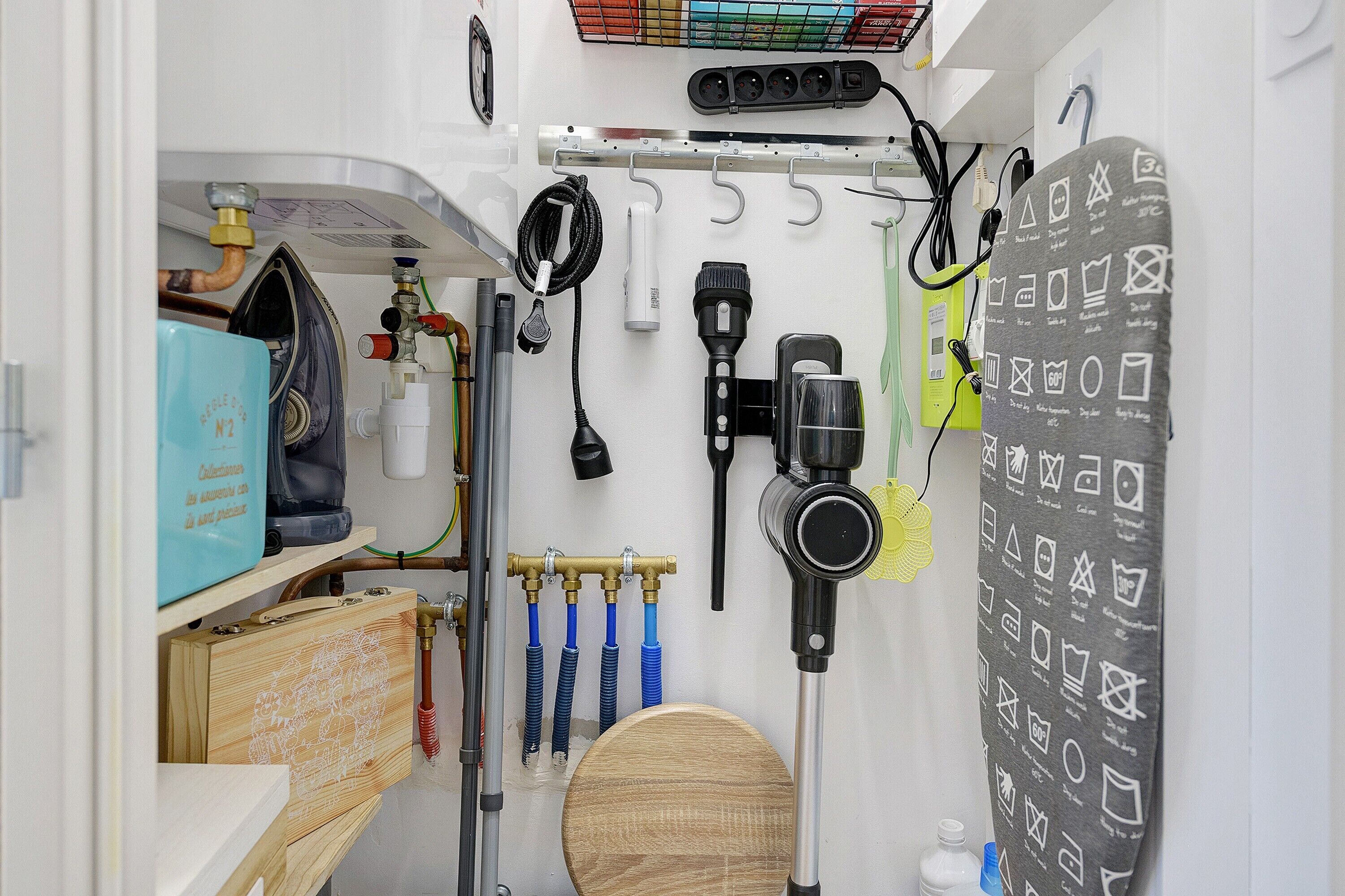 A compact bathroom with a wooden toilet, a towel rack with a patterned towel, and a wall-mounted camera.