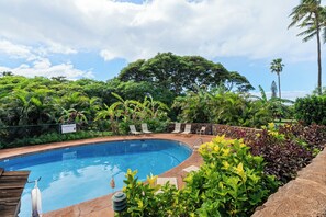Une piscine entourée d’une végétation luxuriante et de palmiers.
