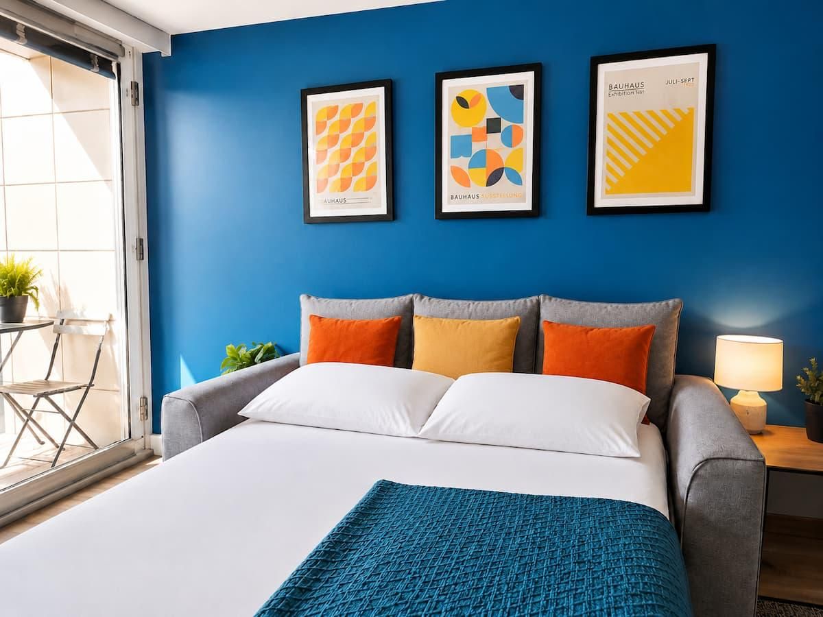 A hotel room with a bed, a blue wall, and three framed artworks.