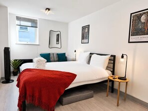 A modern hotel room with a bed, bedside table, lamp, and artwork on the walls. - York Centre Flat - balcony, lift & 2 baths (York)