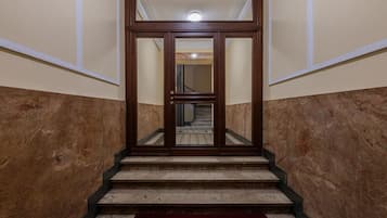 Una escalera que lleva a una puerta espejada, con un tapete rojo en la parte inferior.