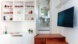 Un bagno moderno con un lavabo, scaffali con articoli da toilette, uno specchio e una TV a parete.