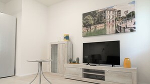 Una sala de estar moderna con un televisor de pantalla plana, una mesa de centro y un cuadro de un paisaje urbano.