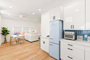 Een moderne keuken met witte kasten, een blauwe koelkast en een inbouwoven.