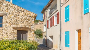 Una calle estrecha con edificios de piedra, puertas de madera y contraventanas.