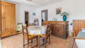 Un comedor con mesa de madera, sillas, un armario y una cama con cabecera.