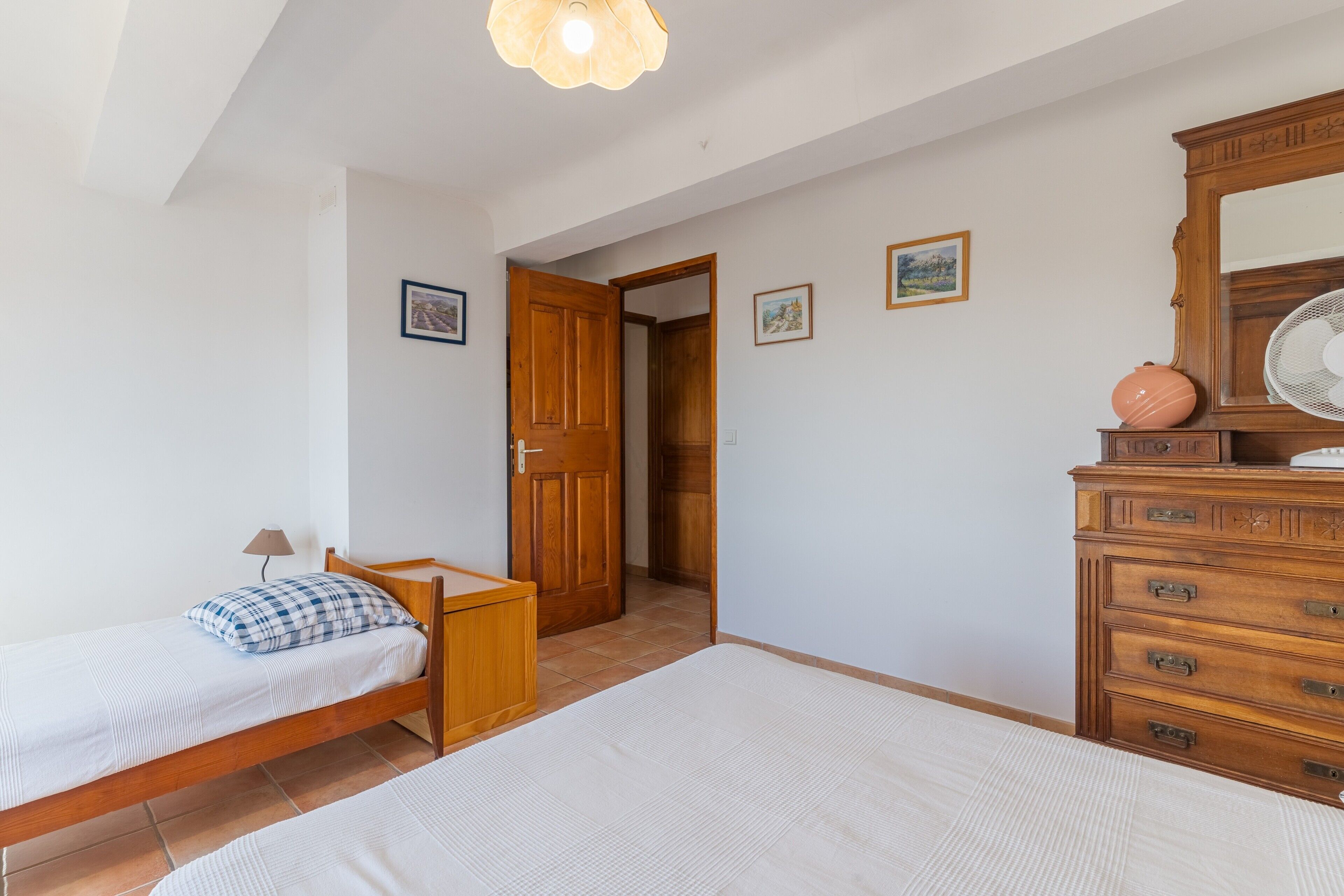 Ein Schlafzimmer mit Bett, Schminktisch, Spiegel und einer Tür zu einem anderen Raum.