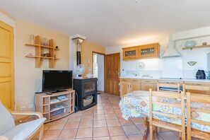 Ein kompakter Wohnraum mit Fernseher, Holzmöbeln, einer kleinen Küche und einem Esstisch.