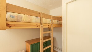 A bunk bed with a wooden ladder and a green cabinet below.