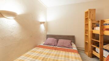 A small bedroom with a single bed, a wooden wardrobe, and a wall-mounted light fixture.