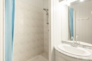 Une salle de bain avec une douche, un lavabo et un miroir.