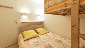 A bunk bed with a headboard, two pillows, and a wall-mounted light fixture.