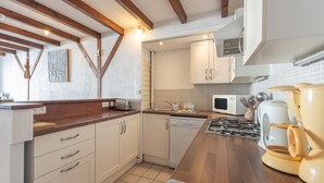 A kitchen with wooden beams, white cabinets, a microwave, and a coffee maker.