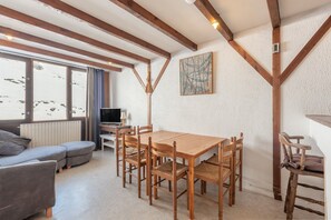 Une pièce chaleureuse avec une table à manger en bois, six chaises, un canapé et un téléviseur.