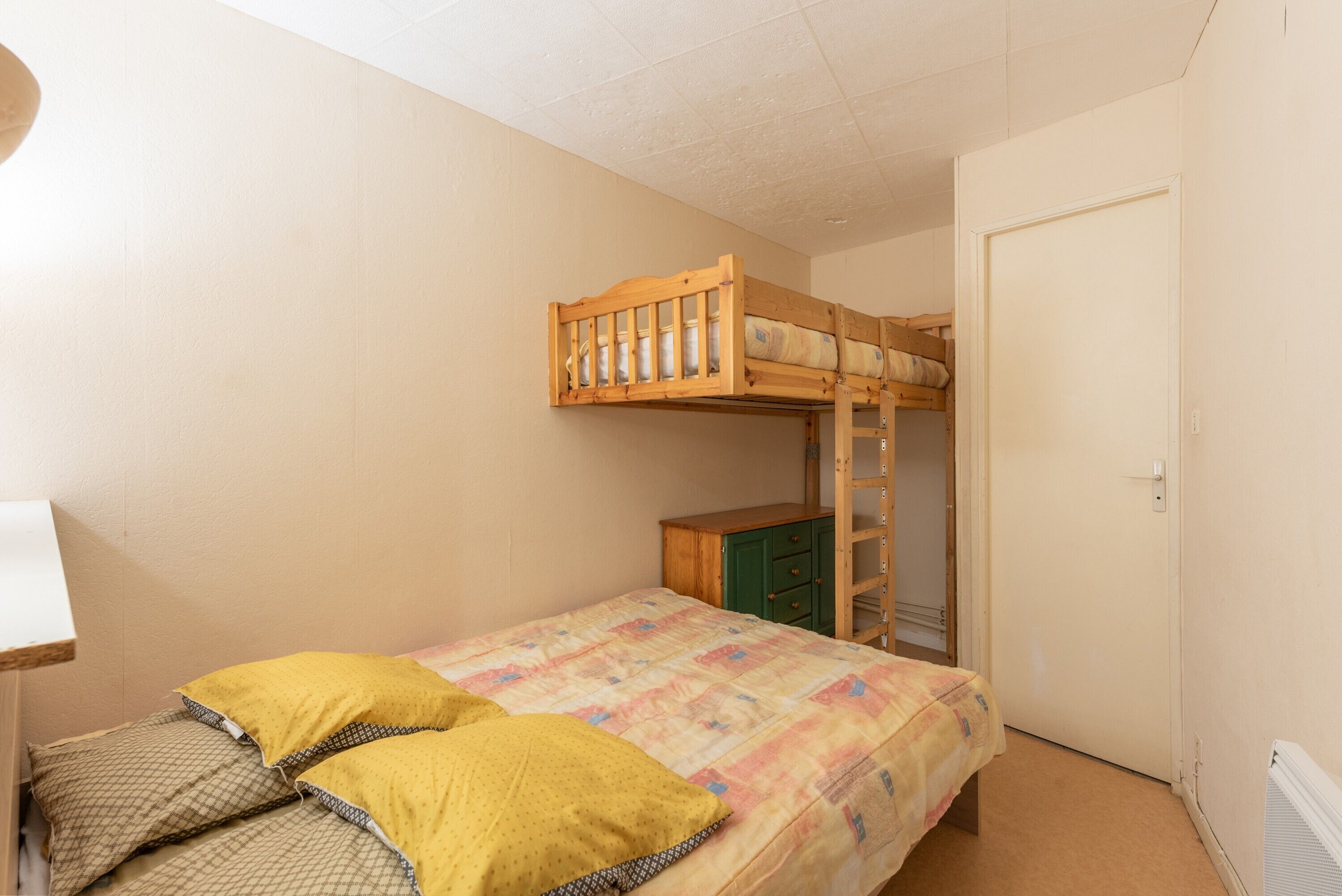A bedroom with a bunk bed, a single bed, a dresser, and a door.