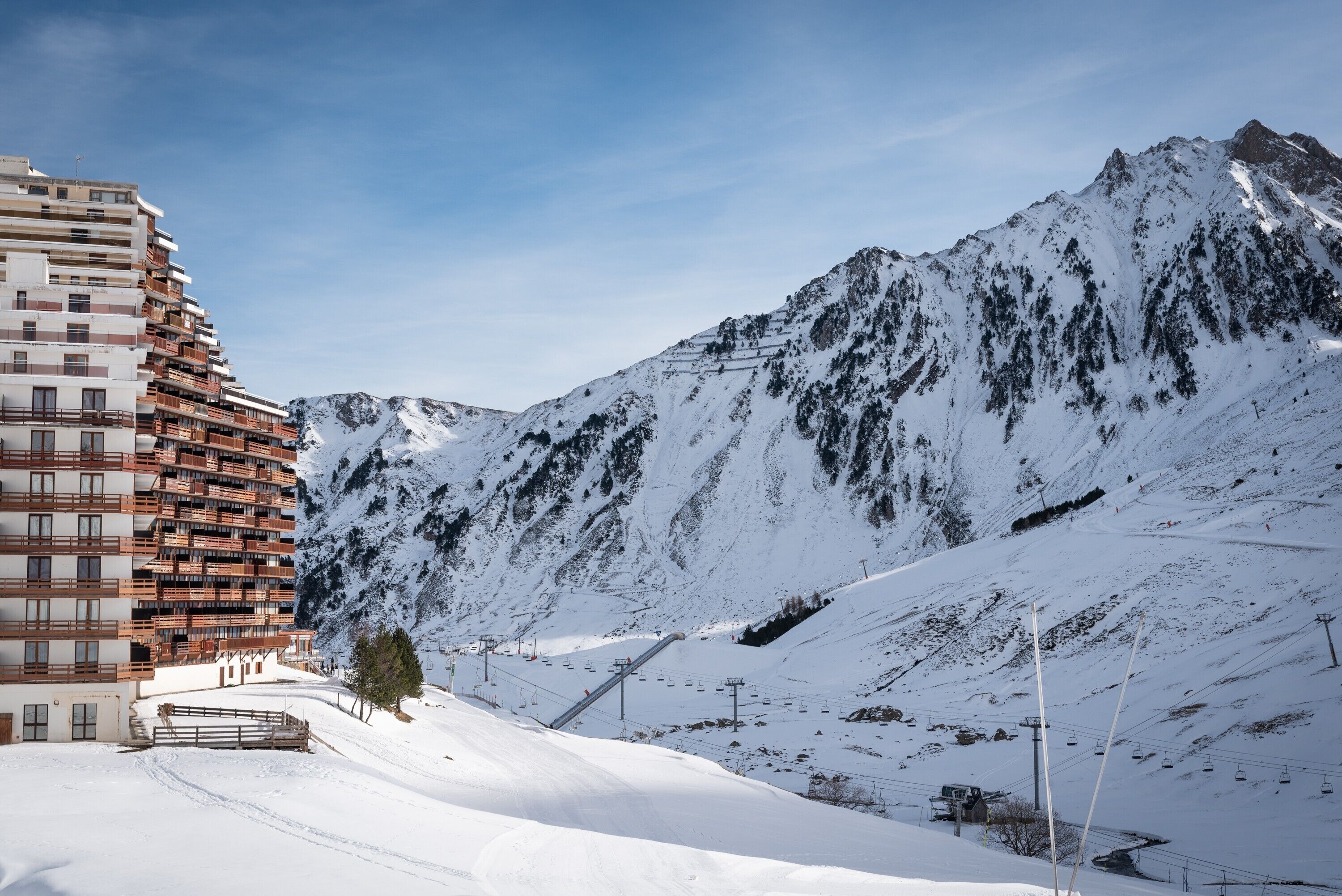A snow-covered mountain with a ski lift and a multi-story building with balconies.