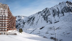 Ein schneebedeckter Berg mit einer Seilbahn und einem mehrstöckigen Gebäude mit Balkonen.
