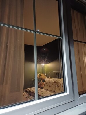 Ein Zimmer mit einem Bett, einem Nachttisch mit einer Lampe und Vorhängen.