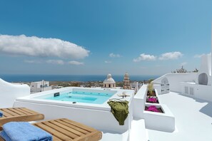 Eine Dachterrasse mit Swimmingpool, Holzliegen und Blick auf das Meer und die Gebäude.