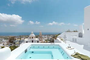 Eine Dachterrasse mit Whirlpool, Blick auf das Meer und weiße Gebäude mit Kuppeldächern.