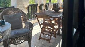 A covered outdoor seating area with wicker furniture and a table, a ceiling fan, and a view of greenery. - Apartment 'Villa Marina' with Sea View, Shared Pool and Air Conditioning (Pula)