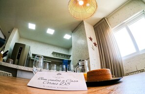 A kitchen with a countertop, a hanging light fixture, and a window with curtains. - MHV Milagres - Casa Coral Curimã D9 (Passo de Camaragibe)