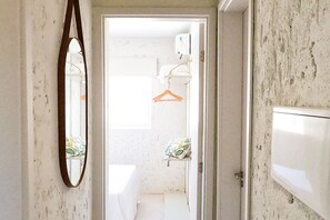 A narrow hallway with a mirror on the left, leading to a bathroom with a toilet, a sink, and a towel rack. - MHV Milagres - Casa Coral Curimã D9 (Passo de Camaragibe)