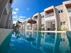 A modern resort with a clear pool, stone facades, and a sunny sky. - MHV Milagres - Casa Coral Curimã D9 (Passo de Camaragibe)