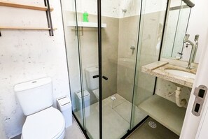 A bathroom with a glass-enclosed shower, a toilet, and a sink with a mirror above it. - MHV Milagres - Casa Coral Curimã D9 (Passo de Camaragibe)