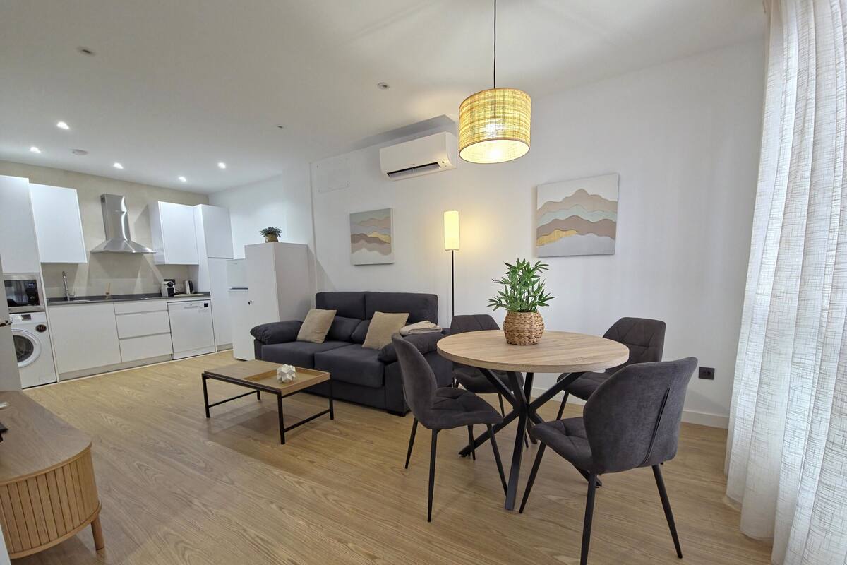 A modern apartment with a dining area, sofa, and kitchen.