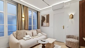A modern living room with a sofa, a round coffee table, and a patterned armchair. - New suite 6 personnes- Saint Germain Notre-Dame (Paris)