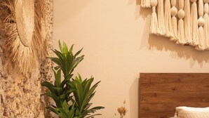 A bedroom with a wooden headboard, a nightstand with a drawer, a potted plant, and a wall-mounted macrame piece. - Boho Suite, Garden and Private Pool in Merida Downtown (Romantic and Exclusive) (Mérida)