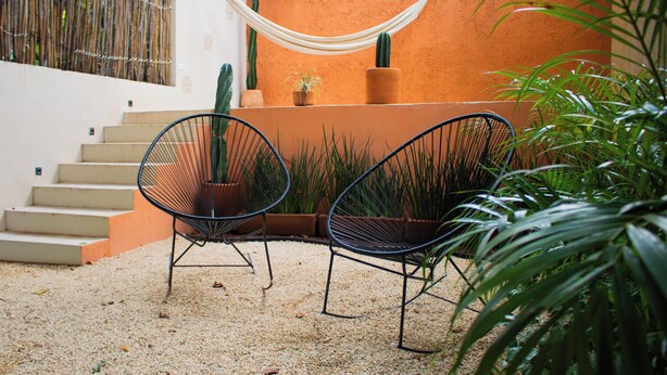 A patio with two chairs, a hammock, and a cactus. - Boho Suite, Garden and Private Pool in Merida Downtown (Romantic and Exclusive) (Mérida)