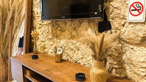 A wooden console table with a flat-screen TV mounted above it, a no-smoking sign, and decorative plants. - Boho Suite, Garden and Private Pool in Merida Downtown (Romantic and Exclusive) (Mérida)
