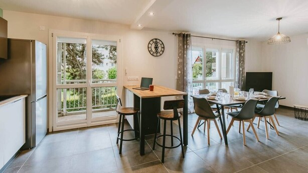 Una cocina moderna con comedor, ventanas amplias y un reloj en la pared.