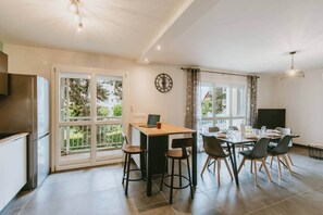 A modern kitchen with a dining area, large windows, and a clock on the wall. - Comfortable 2-bedroom apartment with air conditioning, parking, balcony, and Wi-Fi. (Bassens)