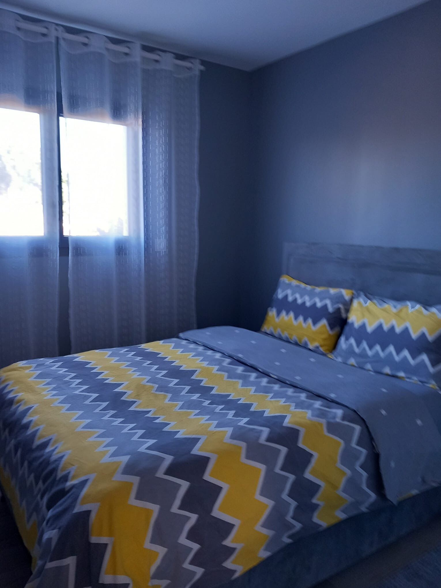 A bedroom with a bed, curtains, and a window.