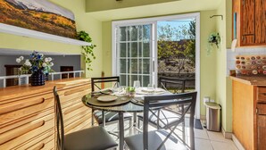 A dining area with a wooden table and chairs, a vase of flowers, and a view of the outdoors. - 6BD Near DT - BBQ Grill, Games & Football Fun (Arvada)