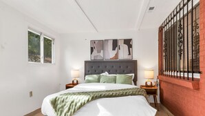 A bedroom with a bed, two bedside tables, a window, and a wall-mounted artwork. - 6BD Near DT - BBQ Grill, Games & Football Fun (Arvada)