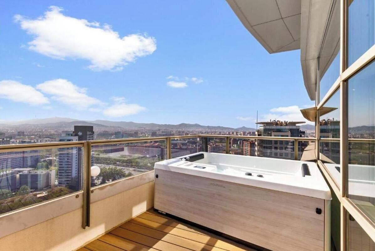 Een balkon met een jacuzzi, houten vloeren en uitzicht op de stad.