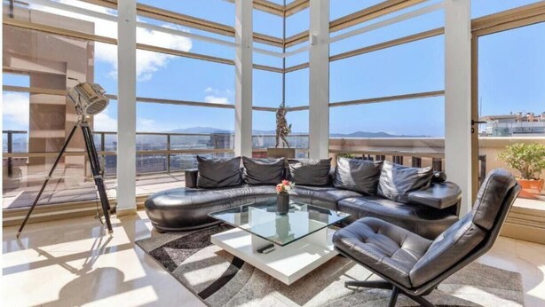 A modern living room with a glass coffee table, leather sofa, and a tripod. - Welcome to The Penthouse – Beachfront Luxury (Barcelona)