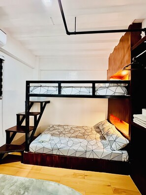 Een stapelbed met beddengoed met een geometrisch patroon, een houten trapje en een klein plankje.