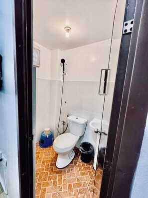 Een kleine badkamer met toilet, bidet en douche.
