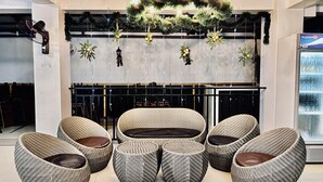 Een moderne lounge met rieten meubels, een decoratieve plafondlamp en een wandgemonteerde display.